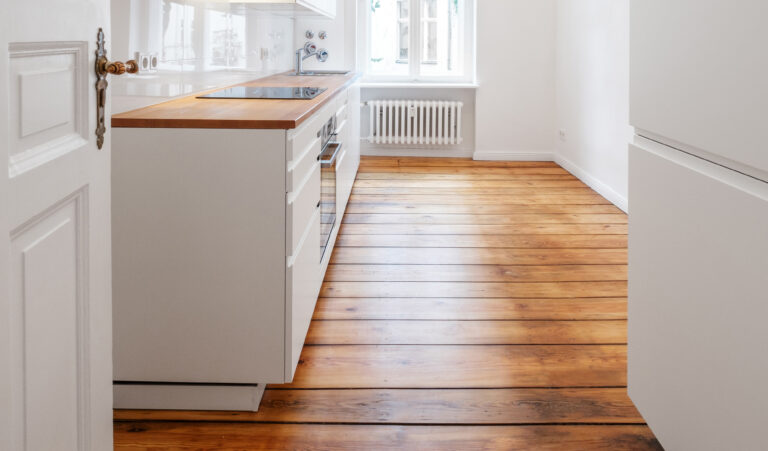 new white kitchenette / kitchen in renovated old building with wooden floor