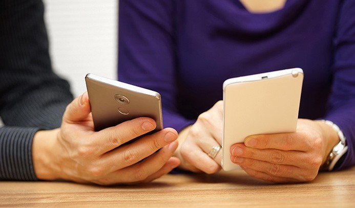 two young adults sharing music and files over mobile smart phones